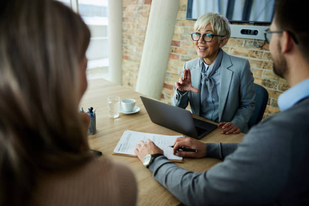 Happy real estate agent talking to her customers during a meeting in the office.